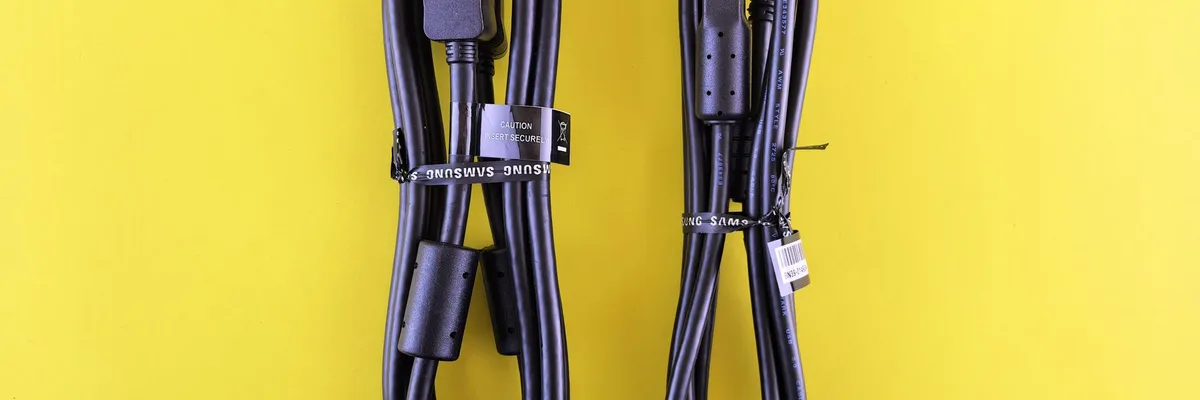Paire de câbles USB Samsung noirs soigneusement disposés sur une surface jaune vif.